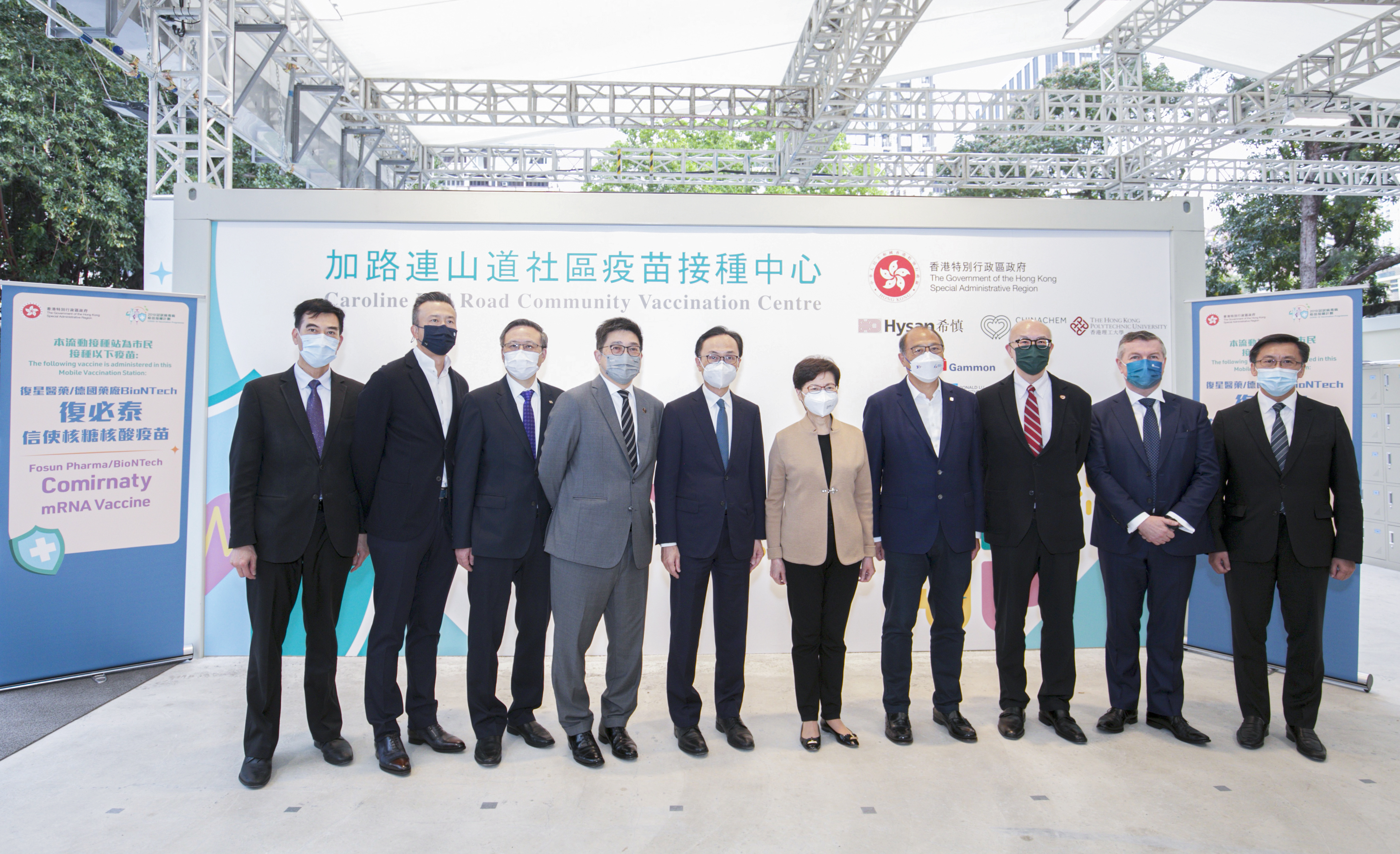 The Chief Executive Carrie Lam (5th from right), Secretary for the Civil Service Patrick Nip (5th from left), Executive Director and CEO of Chinachem Group Donald Choi (3rd from right), Executive Director and Chief Operating Officer of Hysan Development Ricky Lui (4th from left), Chief Executive of Gammon Construction Kevin O'Brien (2nd from right), Chairman of the Council of the Hong Kong Polytechnic University (Poly U) Dr Lam Tai-fai (4th from right) and President of Poly U Prof Teng Jin-guang (3rd from left), East Asia Regional Chairman of Arup Michael Kwok (right), Vice Chairman of Ronald Lu and Partners Bryant Lu (2nd from left) and Managing Director, Property & Buildings, China Region of WSP Colin Chung (left) take a group photo at the Caroline Hill Road pop-up Community Vaccination Centre.